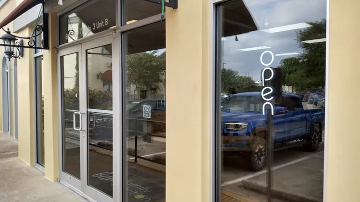 Glass double doors and front windows of a storefront with an open sign