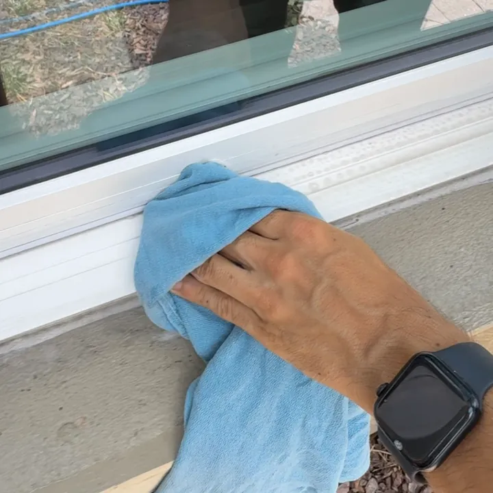 Wiping a window sill with a blue towel