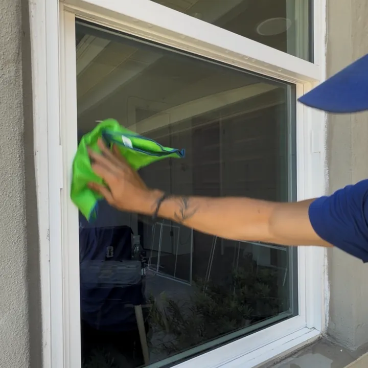 Wiping clean window glass with a green microfiber cloth