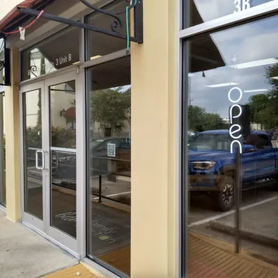 Glass double doors and front windows of a storefront with an open sign